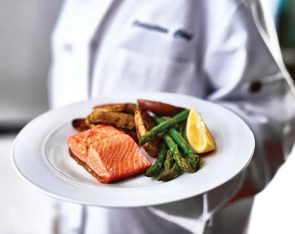 Whispering Pines Chef Created Meals, chef delivering a finished dish.